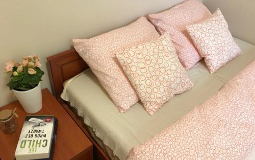a bed with pink pillows and a table with a book at Apartamenty Winniczki in Pobierowo