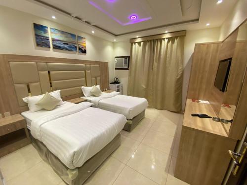 um quarto de hotel com duas camas e uma televisão em ديار الفارس em Iambo