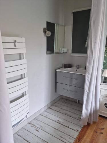 bagno bianco con lavandino e specchio di Villa climatisée avec piscine à LEGE CAP FERRET a Lège-Cap-Ferret