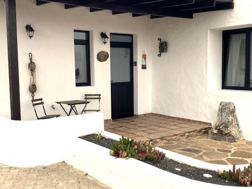 a white house with a table and a door at Casa Del Amigo Carmelo in Ye