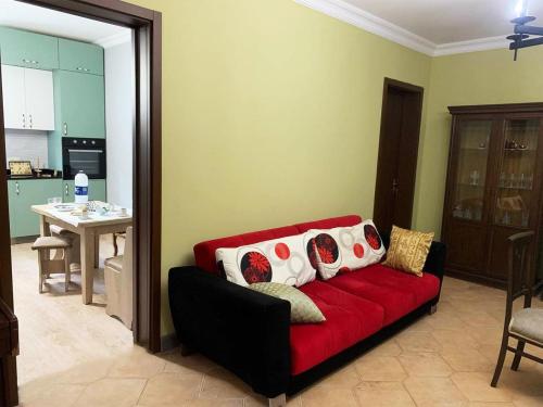 a red couch in a living room with a kitchen at Nargizi guest house in Gonio