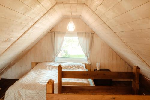 Cama en habitación pequeña con ventana en Beneháti kunyhók, en Mátrafüred