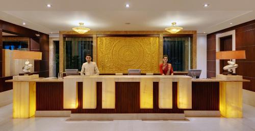two people standing at a reception desk in a lobby at Ramada Plaza by Wyndham JHV Varanasi in Varanasi