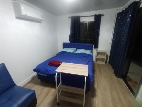 um pequeno quarto com uma cama azul e uma mesa em PA House Apartment em Banguecoque
