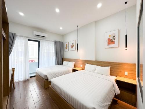a hotel room with two beds and a window at HAKU HOME Mini Apartments & Homestay in Quy Nhon