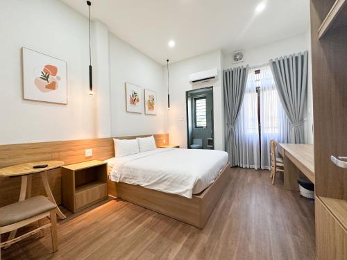 a bedroom with a bed and a table and a desk at HAKU HOME Mini Apartments & Homestay in Quy Nhon
