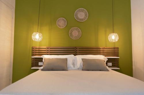a bedroom with a large white bed with green walls at Sunrise Sardinia Posada in Posada