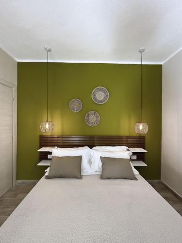 a bedroom with a large bed with a green wall at Sunrise Sardinia Posada in Posada