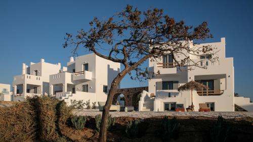 un edificio blanco con un árbol delante en Nymphée Luxury Villas, en Agia Anna de Naxos
