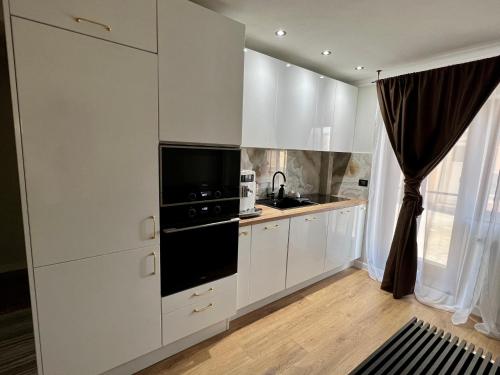 a kitchen with white cabinets and a black appliance at Kalim’s apartment in Arad