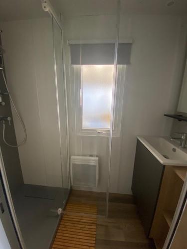 uma casa de banho com um chuveiro e um lavatório. em Mobil-home Les Dunes de Contis em Saint-Julien-en-Born