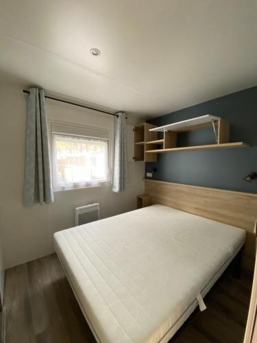 a small bedroom with a bed and a window at Mobil-home Les Dunes de Contis in Saint-Julien-en-Born