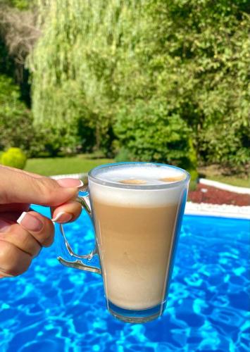 a person holding a glass of coffee on a table at CASA DRENCOVA SRL in Berzasca