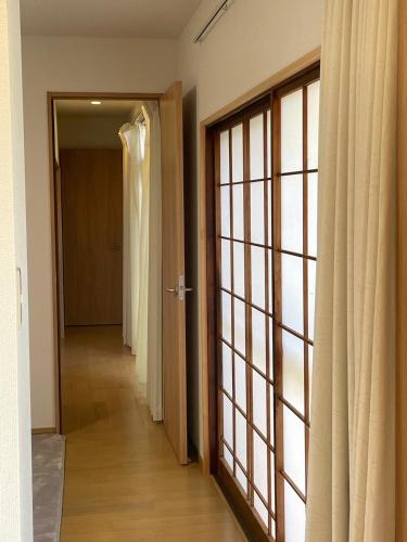 a hallway with an open door and a door with curtains at 青梅森の宿 in Ome