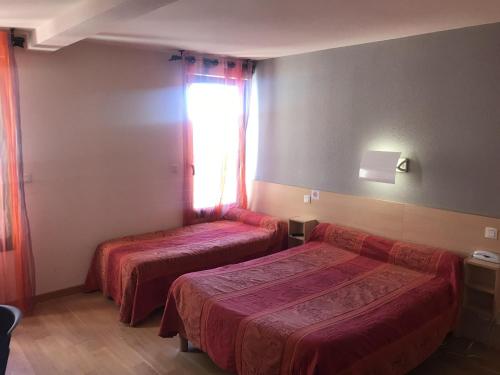 a hotel room with two beds and a window at Aux berges de Pareloup in Salles-Curan