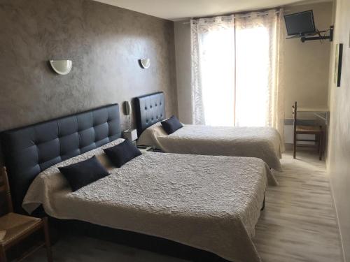 a hotel room with two beds and a window at Aux berges de Pareloup in Salles-Curan