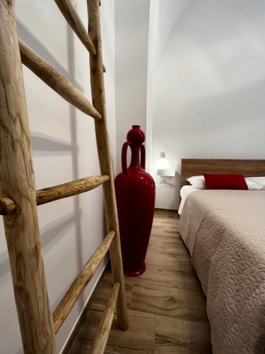 a red vase sitting next to a bed in a room at Dimora Nonno Ciccio in Polignano a Mare