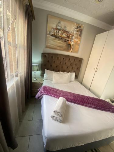 a bedroom with a bed with a purple blanket on it at Menlyn Mews Guesthouse in Pretoria