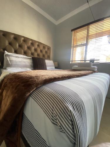 a bedroom with a large bed with a blanket on it at Menlyn Mews Guesthouse in Pretoria