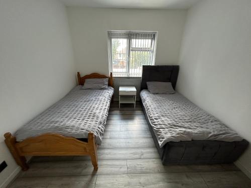 - 2 lits jumeaux dans une chambre avec fenêtre dans l'établissement Lovely 3 Bedroom Entire Home With Street Parking - Close to NEC, BHX Airport - Sleeps 6 Guests IDEAL FOR CONTRACTORS & FAMILIES, à Birmingham