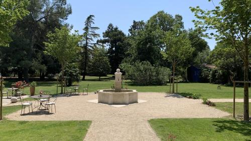 a park with a fountain and tables and chairs at Domaine de Rhodes B&B in Avignon