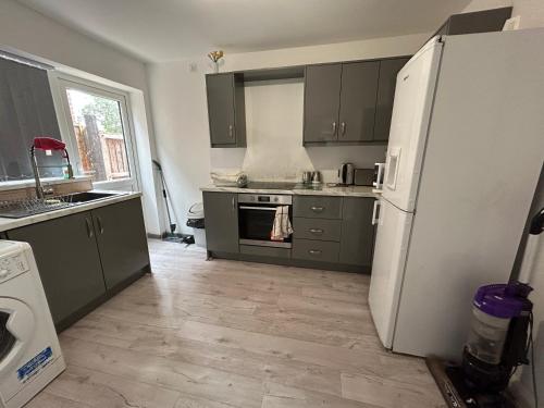 a kitchen with green cabinets and a white refrigerator at Lovely 3 Bedroom Entire Home With Street Parking - Close to NEC, BHX Airport - Sleeps 6 Guests IDEAL FOR CONTRACTORS & FAMILIES in Birmingham