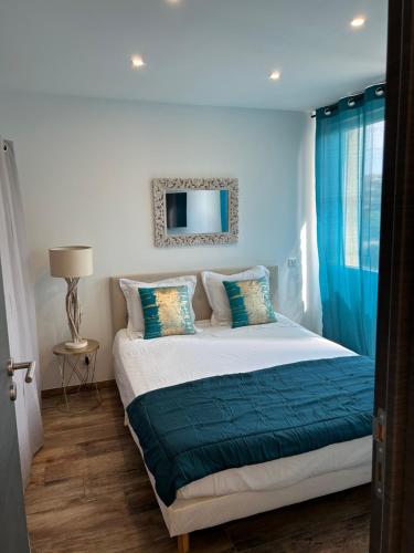 une chambre avec un lit avec des rideaux bleus et un miroir dans l'établissement Très bel appartement à Ajaccio, à Ajaccio