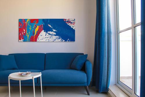 a blue couch in a living room with a painting at CityScape Gzira Holiday Apartments and Penthouse in Il-Gżira