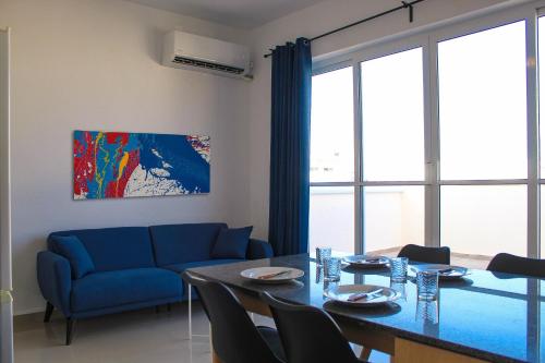 ein Wohnzimmer mit einem Tisch und einem blauen Sofa in der Unterkunft CityScape Gzira Holiday Apartments and Penthouses By ShortletsMalta in Gżira