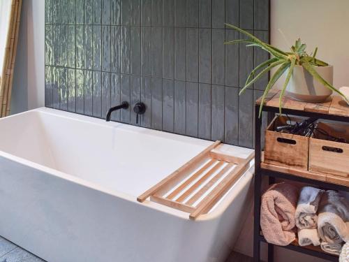 a white bath tub in a bathroom with a plant at Holiday home GAMLE FREDRIKSTAD in Trolldalen