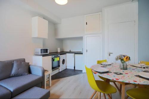 a kitchen and living room with a table and a couch at Cosy & Central Broughton 2BR Apt near City Centre in Edinburgh