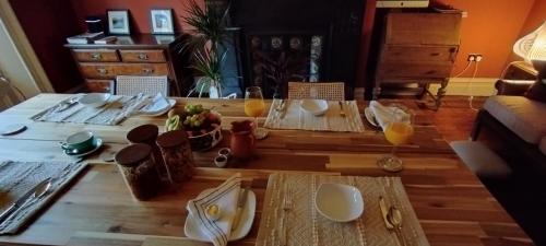 einem Holztisch mit Teller und Gläsern Orangensaft in der Unterkunft Merchant House in Bootle