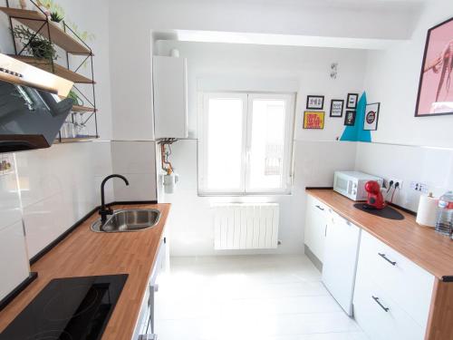 Una cocina con gabinetes blancos y un fregadero. en XOXO - Arco, en Ponferrada