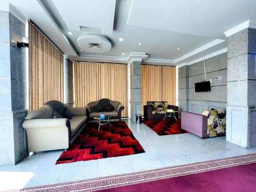 Relax Inn Furnished Apartments Hawally في الكويت: غرفة معيشة مع أريكة وسجادة حمراء
