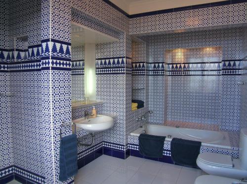 a bathroom with blue and white tiled walls and a tub and sink at Hotel Alhambra in La Orotava