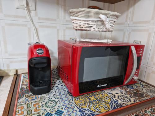 un microondas rojo y un teléfono móvil en una mesa en Alcivico26 en Alghero