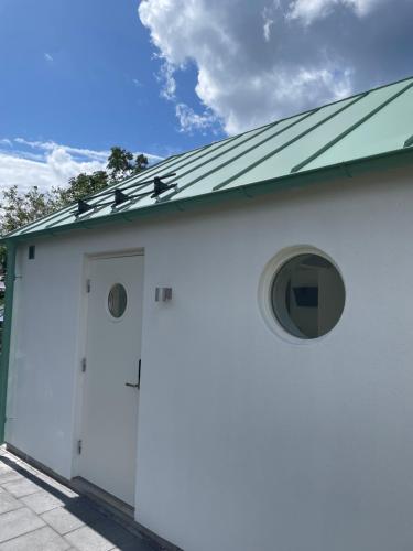 a white building with a door and a green roof at Lilla kyrkhuset på Råå in Helsingborg