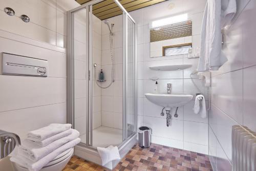 a white bathroom with a shower and a sink at Landhotel Fuchs in Eisenbach