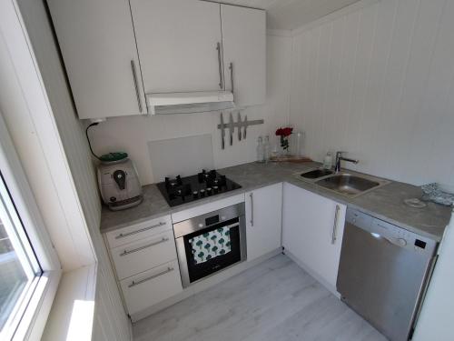 a small kitchen with white cabinets and a sink at Guesthouse with terrace in Arendal