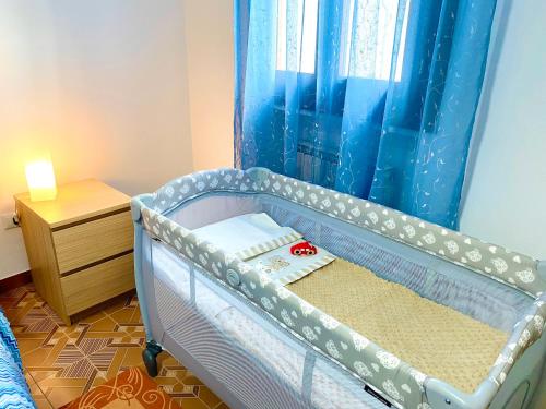 a baby crib in a bedroom with a blue curtain at HOME - Alessandra Holiday House in Piove di Sacco