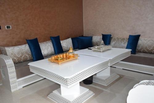 una mesa blanca y un sofá con almohadas azules en Ghazalle Oasis Hotel 1, en El Biar