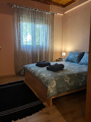a bedroom with a bed with blue sheets and a window at Το πετρινο σπιτι του Καστρη! Με θεα τα Μετεωρα in Kalabaka