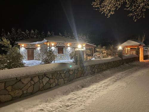 a house covered in snow at night with lights at Το πετρινο σπιτι του Καστρη! Με θεα τα Μετεωρα in Kalabaka
