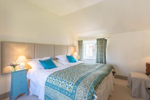 een slaapkamer met een groot bed met blauwe kussens bij Storm Cottage in Langham