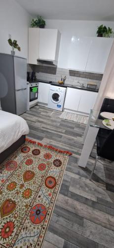 a kitchen with white cabinets and a rug on the floor at Studio Flat in Camden in London