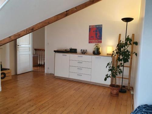 a kitchen with white cabinets and a wooden floor at 2 chambres dans une maison proche de Paris et du Stade de France in Enghien-les-Bains