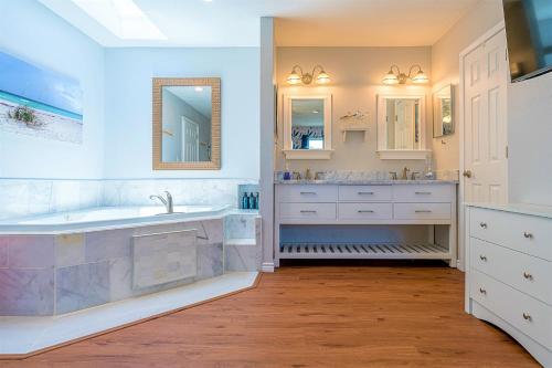 a white bathroom with a tub and a sink and a tub at Hot Tub and Jacuzzi Suite! 100 steps from spacious beach and Jetty park! Generations Retreat Sleeps 26 in Surfside Beach