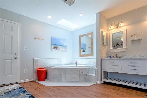 a white bathroom with a tub and a sink at Hot Tub and Jacuzzi Suite! 100 steps from spacious beach and Jetty park! Generations Retreat Sleeps 26 in Surfside Beach