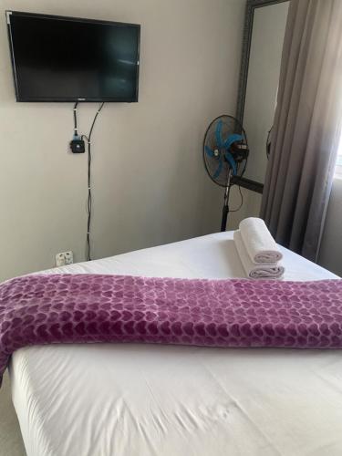a purple blanket on a bed in a room at Menlyn Mews Guesthouse in Pretoria