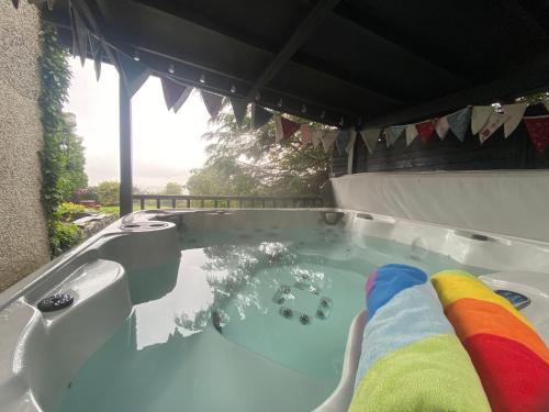 uma banheira de hidromassagem com uma toalha de arco-íris em Carreg Y Garth Isaf - Hot Tub Nr Zip World em Bangor